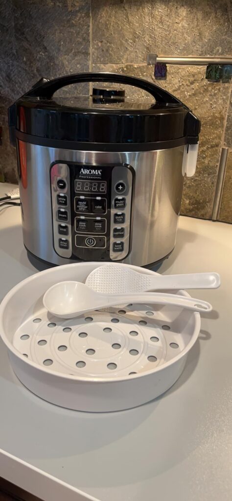 digital rice cooker with steaming vegetables on countertop